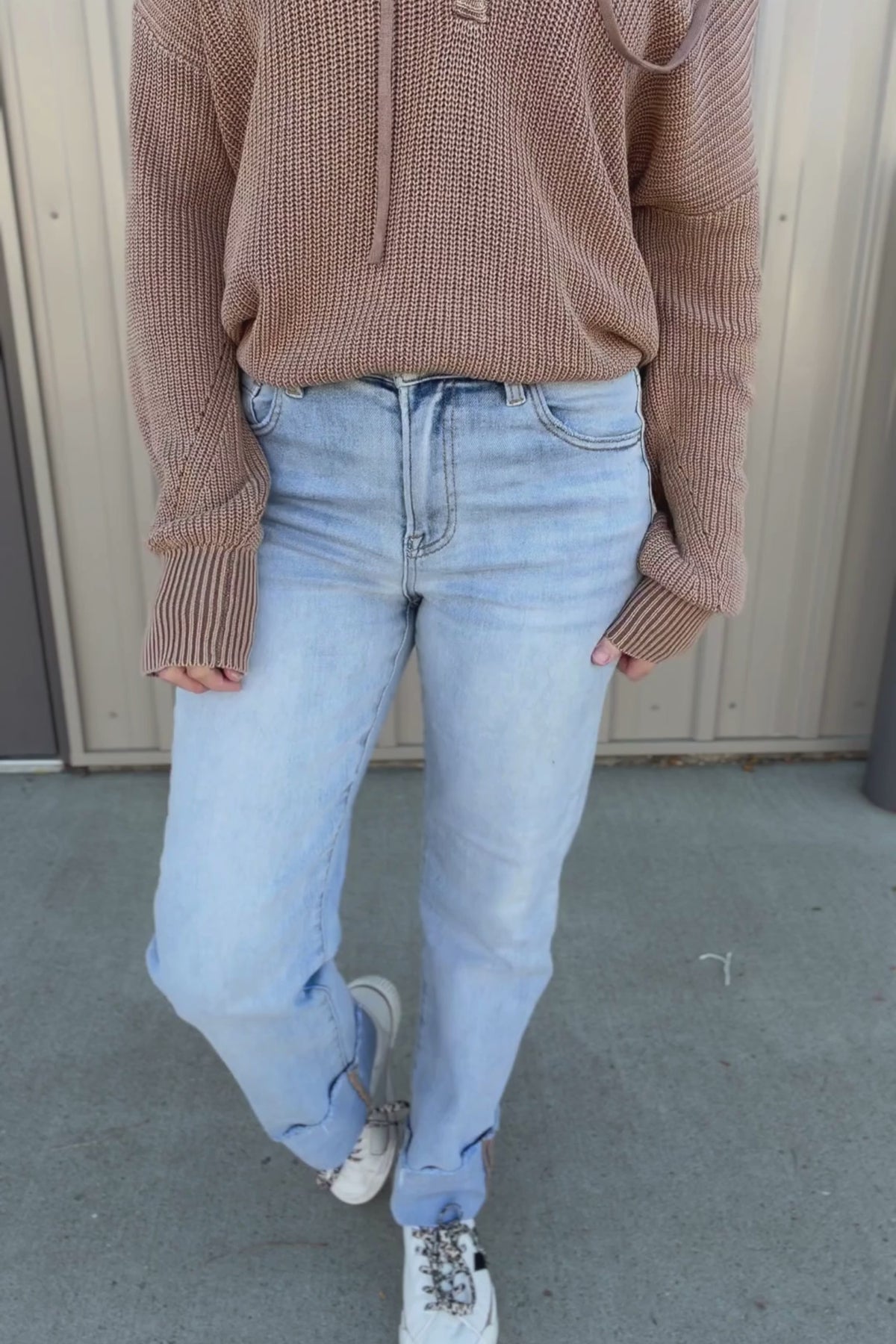 Video of someone trying on light blue jeans against a neutral background